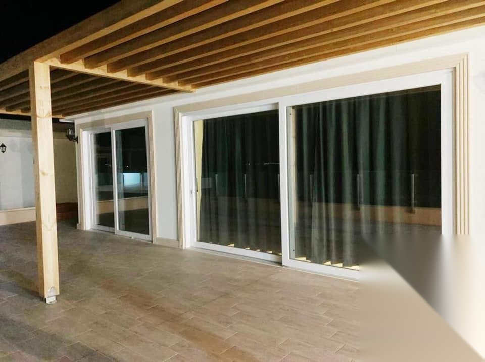 Baies coulissantes aluminium blanc sous pergola bois